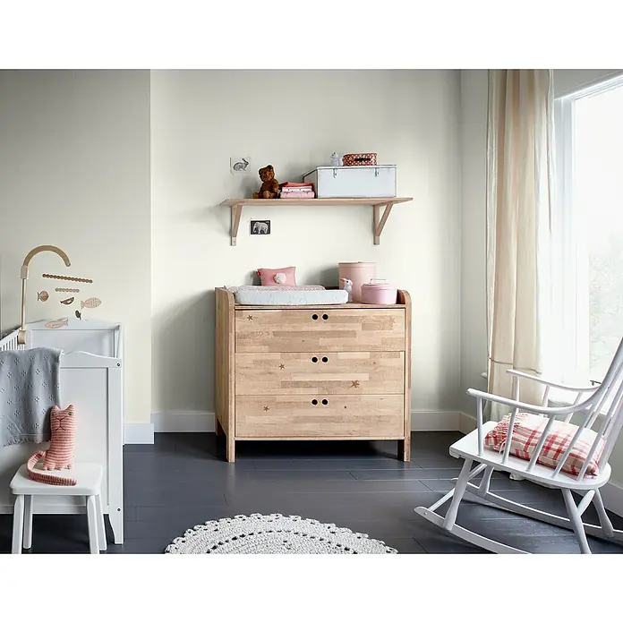 Bruguer Elegance Pintura para paredes - Blanco espuma, Mate, 4 l - Habitación infantil luminosa con cómoda de madera y mecedora blanca junto a la ventana, creando un ambiente tranquilo. Ideal para bebés y niños.