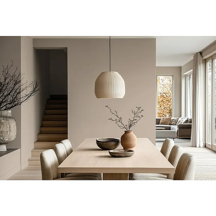 Bruguer Elegance Pintura para paredes - Marrón beige, Mate, 4 l - Comedor luminoso con una lámpara colgante escultural sobre una mesa y sillas de madera, creando un ambiente cálido y acogedor.