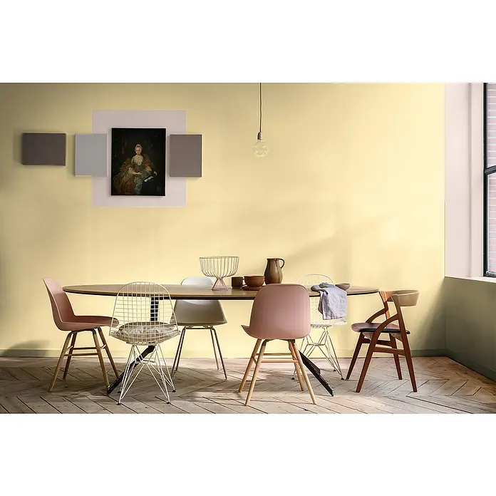 Bruguer Elegance Pintura para paredes - Amarillo destello, Mate, 4 l - Un comedor con una mesa ovalada rodeada de seis sillas de diseños variados, bajo iluminación elegante y arte.