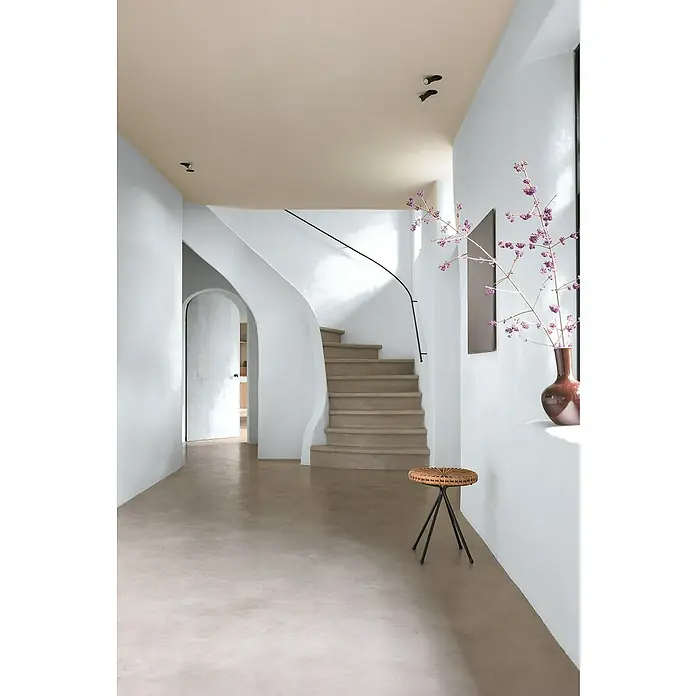 Bruguer Elegance Pintura para paredes - Gris neutro, Mate, 4 l - Recibidor acogedor con escaleras curvas, taburete redondo y un elegante jarrón de flores junto a la ventana. La paleta de colores es tranquila y armónica.