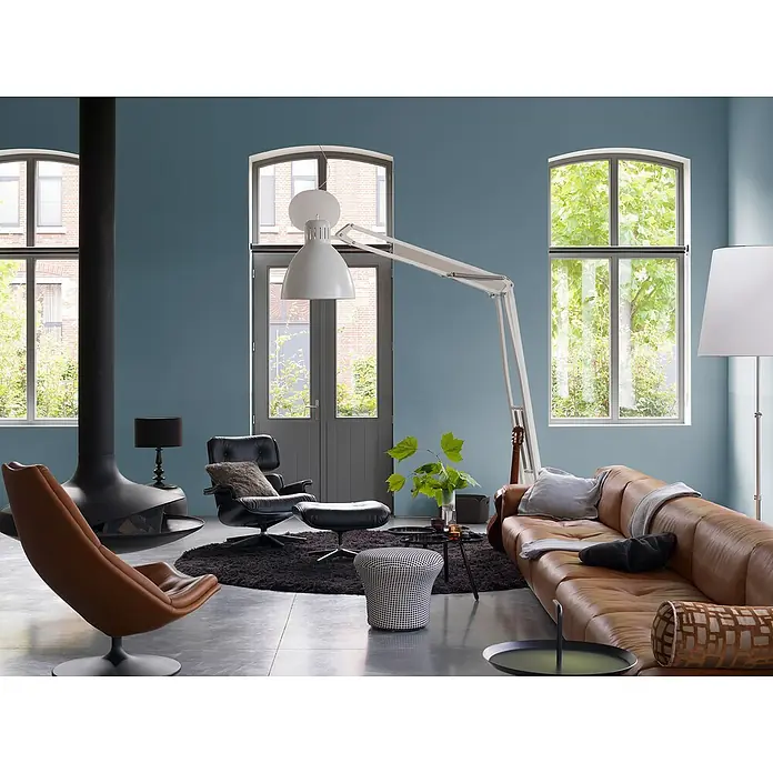 Bruguer Elegance Pintura para paredes - Azul naval, Mate, 4 l - Salón con sofá de cuero, sillones, lámpara de pie y chimenea. Ambiente acogedor con muebles modernos y colores cálidos.