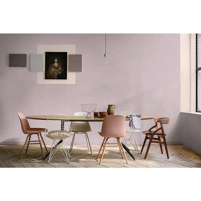Bruguer Elegance Pintura para paredes - Rosa chic, Mate, 4 l - Un elegante comedor con una mesa ovalada rodeada de sillas variadas y una decoración de pared elegante.