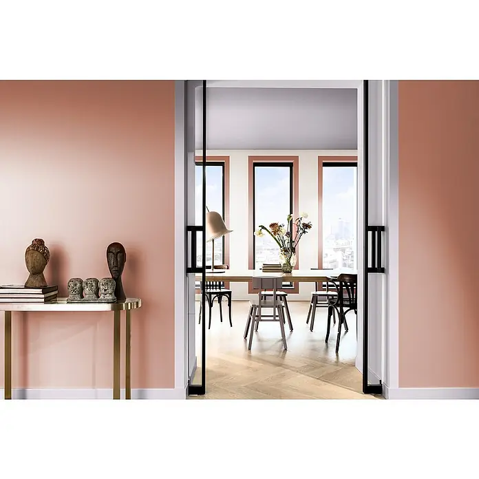 Bruguer Elegance Pintura para paredes - Rojo amapola, Mate, 4 l - Interior elegante con mesa consola, esculturas y vista a través de una puerta a un comedor luminoso y moderno.