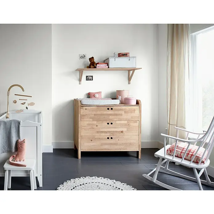 Bruguer Elegance Pintura para paredes - Blanco nube, Mate, 4 l - La imagen muestra una habitación infantil con una cómoda de madera clara adornada con estrellas y un cambiador en la esquina.