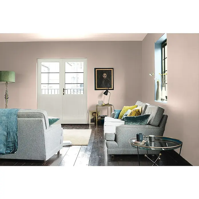 Bruguer Elegance Pintura para paredes - Rosa antiguo, Mate, 4 l - Elegante sala de estar con sofá y sillones grises, acentuada con cojines coloridos y una mesa de centro elegante. Las paredes claras crean un ambiente acogedor.