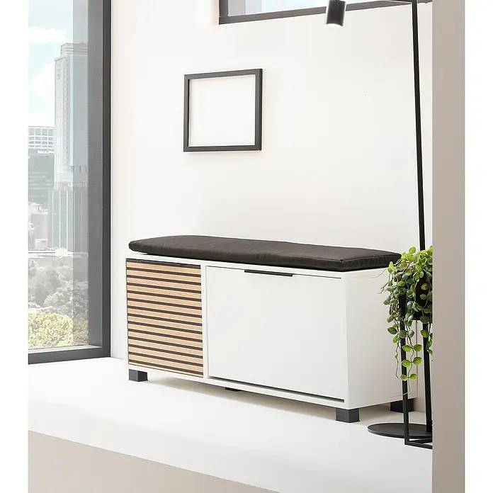 Schildmeyer Loft Schuhbank - 33 x 98,4 x 47,2 cm, Weiß/Akustik-Dekor - Einrichtungsidee mit einer weißen Bank mit Schubladen und einer grauen Sitzfläche, die unter einem leeren Bilderrahmen steht.