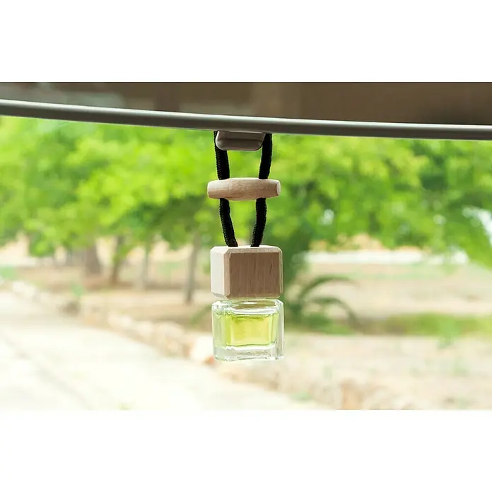 Ambientador de coche para colgar - Limón, 8 sem. - Ambientador colgante con detalles de madera y una pequeña botella de vidrio llena de un líquido amarillento.