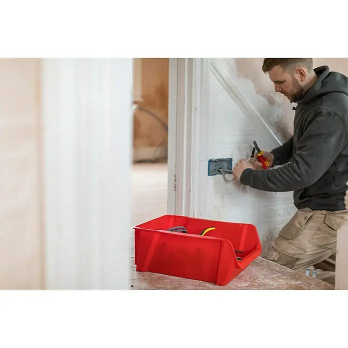 Stanley Sichtlagerkasten - Größe: 5, Rot - Rote Stapelbox im Vordergrund, Elektriker arbeitet an Kabeln im Hintergrund. Ideal zur Aufbewahrung von Werkzeugen und Materialien.