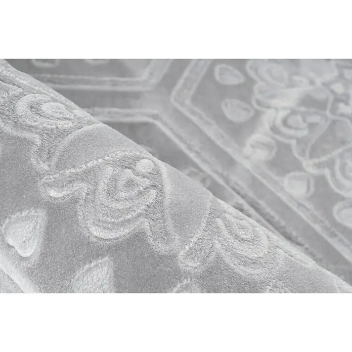 Kayoom Kurzflorteppich Monroe II - Grau/Blau, 230 x 160 cm, 100 % Polyester - Nahaufnahme eines hellgrauen Teppichs mit einem eleganten, floralen Muster, das dem Design eine luxuriöse Note verleiht.