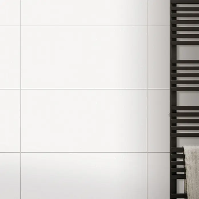 DryTile Wandfliese Palazzo Strukturiert Plast - 30 x 60 cm, Weiß, Glänzend - Nahaufnahme einer schwarzen Handtuchheizung an einer weißen Fliesenwand, die ein modernes und minimalistisches Design zeigt.