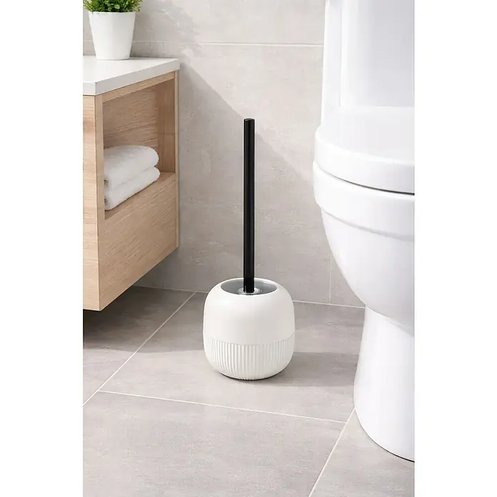 Spirella Gino Escobillero - Altura: 37 cm, Plástico (ABS), Blanco - Una foto de cerca de un cepillo de baño blanco con mango negro, de pie en el suelo del baño junto a un inodoro.