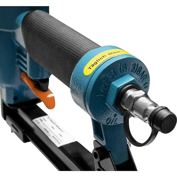 Güde Druckluft-Klammergerät KN 14 - Schwarz/Blau, Stärke: 0,95 mm - Nahaufnahme eines blauen Druckluftnaglers mit schwarzem Griff und einem gelben Aufkleber mit der Aufschrift "Täglich ölen!".