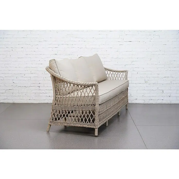 Sunfun Conjunto de muebles Soraya - 4 pzs., Ratán sintético/Aluminio/Poliéster, Beige/Gris - Elegante sofá de ratán con cojines beige contra una pared de ladrillos blancos. El sofá ofrece comodidad y estilo para cualquier espacio.