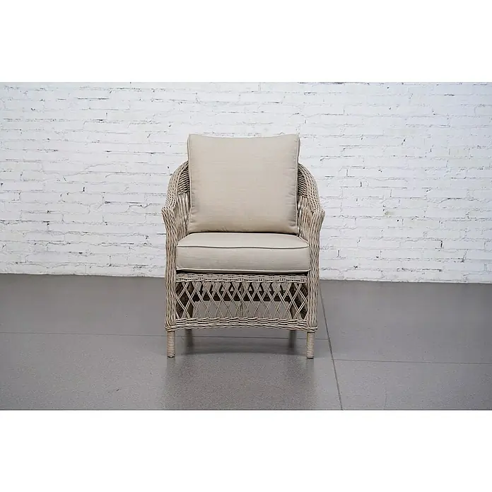 Sunfun Conjunto de muebles Soraya - 4 pzs., Ratán sintético/Aluminio/Poliéster, Beige/Gris - Primer plano de una silla de mimbre con cojines beige contra una pared de ladrillo blanco. La silla ofrece confort y estilo.