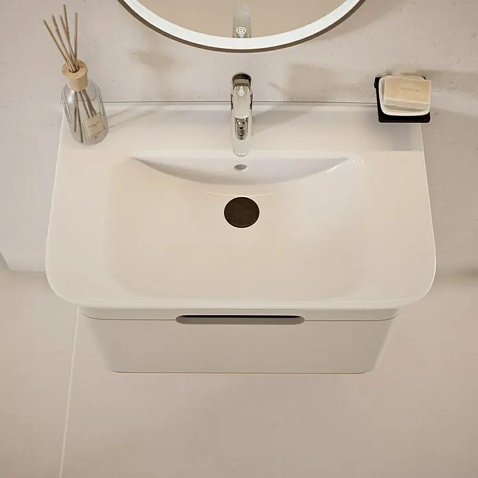 VitrA Sento Badmöbel-Set Sento - 80 cm, Hellgrau, Griffmulde - Aufnahme eines modernen, weißen Waschbeckens mit Armatur, Seife und Duftstäbchen in einem stilvollen Badezimmer.