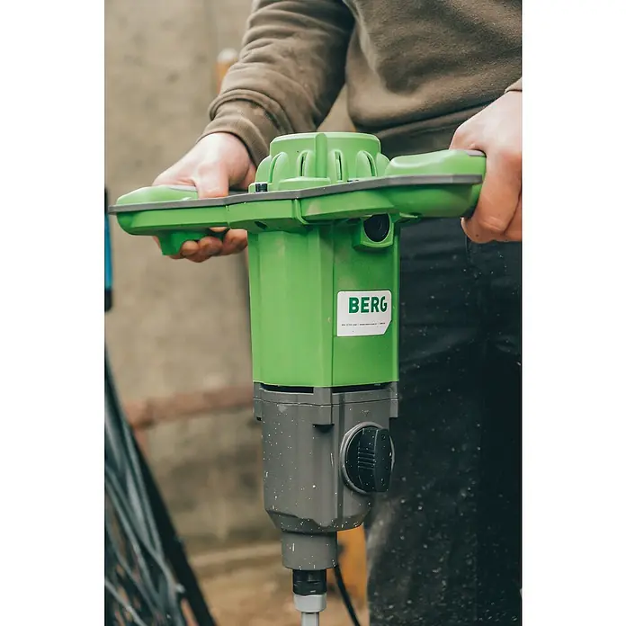 Berg Handrührwerk MX 19 - 1.850 W, Mischvolumen: 200 l - Nahaufnahme einer Person, die einen grünen Berg-Betonmischer hält, der für effizientes Mischen konzipiert ist.\n