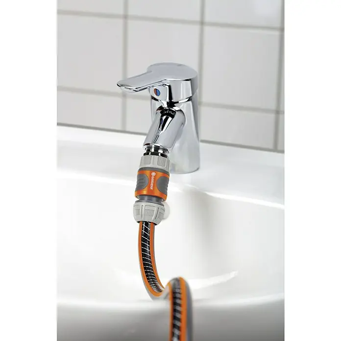 Gardena Gerätestück - Außengewinde: 26,5 mm (G 3/4“), Geeignet für: Wasserhähne mit Perlstrahlkopf - Nahaufnahme eines Wasserhahns mit Gardena-Schlauchanschluss, der einen flexiblen Gartenschlauch befestigt, ideal für Bewässerung.
