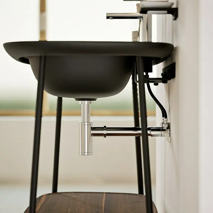 VitrA Plural Badmöbel-Set - Gesamtbreite Badmöbel: 99,5 cm, Schwarz/Eiche Dunkel, Matt, 3 -tlg. - Detailaufnahme eines modernen, schwarzen Waschbeckens mit freiliegendem Siphon und minimalistischem Design.