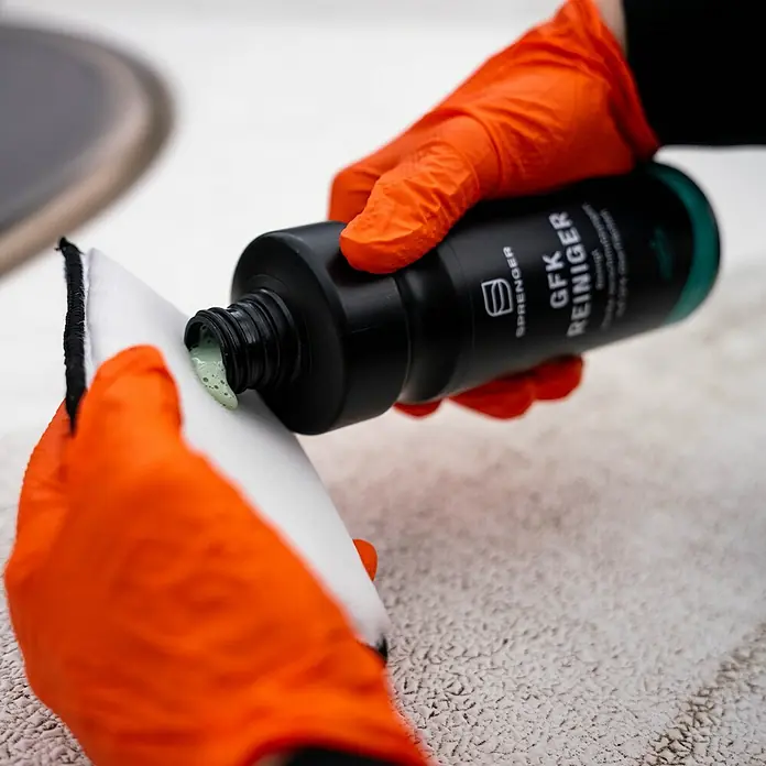 Sprenger Bootsreiniger GFK - 500 ml - Auftragen von Sprenger GFK Reiniger auf einen Applikator. Das Produkt ist in einer schwarzen Flasche mit grünen Akzenten.