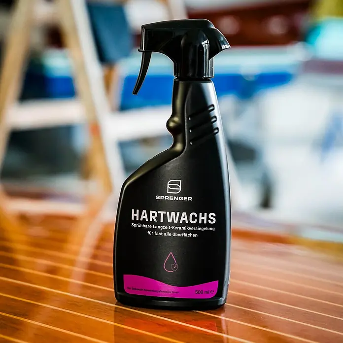 Sprenger Hartwachs-Politur - 500 ml - Das Bild zeigt eine Sprühflasche HARTWACHS Keramikversiegelung von Sprenger auf einem Tisch. Schwarze Flasche mit pinkfarbenem Etikett.