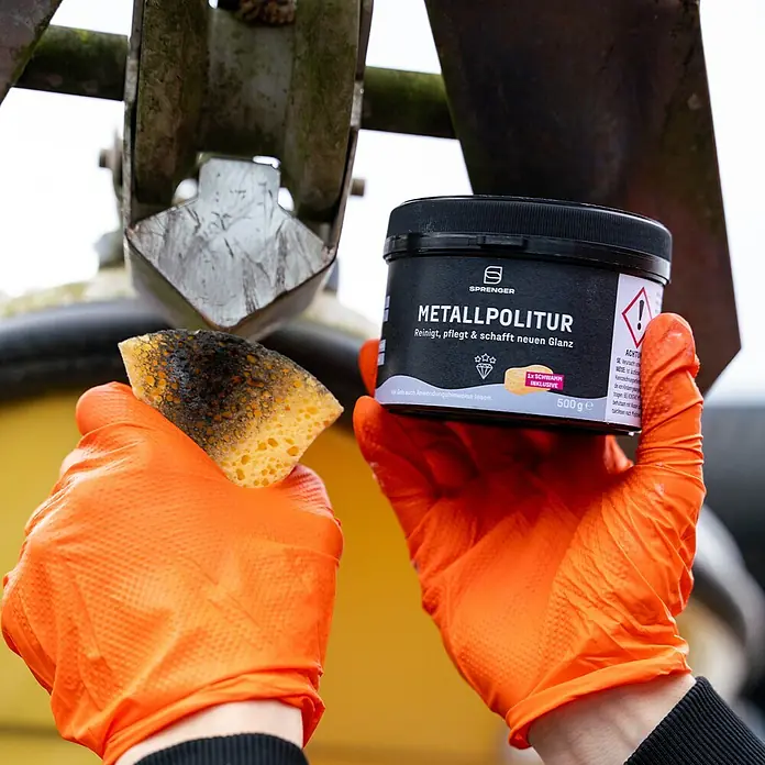 Sprenger Metall-Politurpaste inkl. Schwamm - 500 g - Bild von Sprenger Metallpolitur, die reinigt, pflegt und neuen Glanz verleiht, zusammen mit einem Schwamm in orangefarbenen Handschuhen.