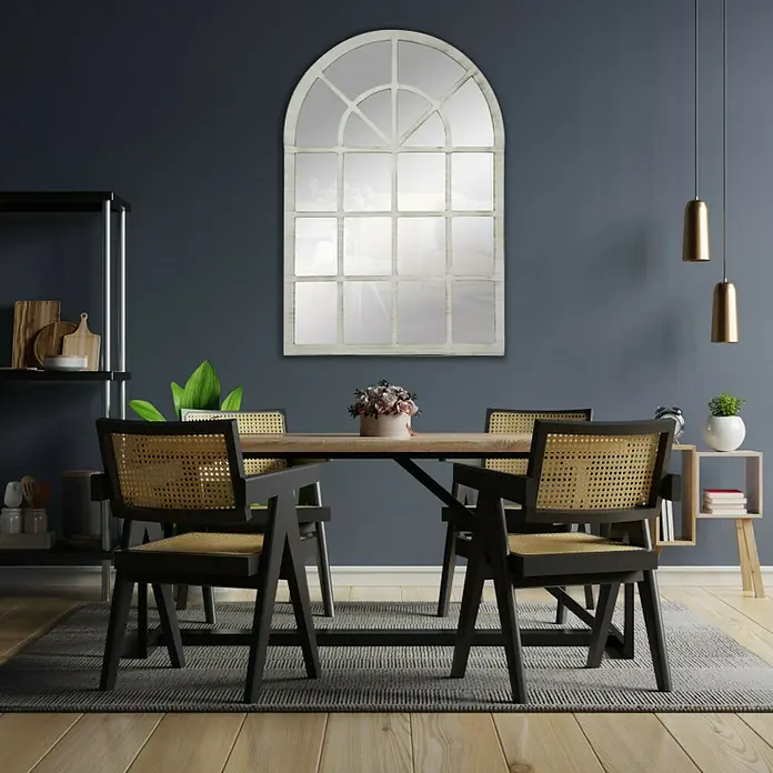 Espejo de pared Catania - 70 x 100 cm, Blanco betún - Un elegante comedor que exhibe un llamativo espejo de ventana arqueada sobre una mesa de madera con elegantes sillas de ratán.