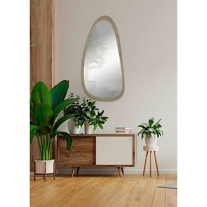 Espejo de pared Prisma - 58 x 118 cm, Roble - Interior decorativo con un espejo asimétrico con marco de madera sobre un aparador con plantas y decoración minimalista.