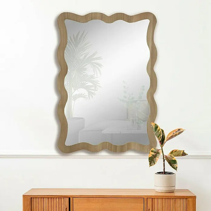Espejo de pared Cube - 64 x 89 cm, Roble - Un elegante espejo de pared con un marco de madera ondulado, colocado sobre un mueble de madera con una planta de interior.