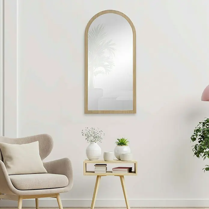 Espejo de pared Arco - 58 x 118 cm, Roble - Interior elegante con un espejo alto con marco de madera sobre una mesa auxiliar que exhibe jarrones y libros.