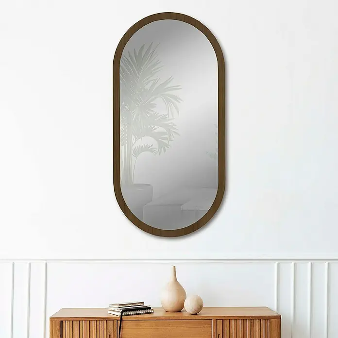 Espejo de pared Alba - 58 x 118 cm, Tabaco - Elegante espejo ovalado con marco de madera montado en la pared sobre una cómoda con decoraciones, creando un aspecto elegante y moderno.
