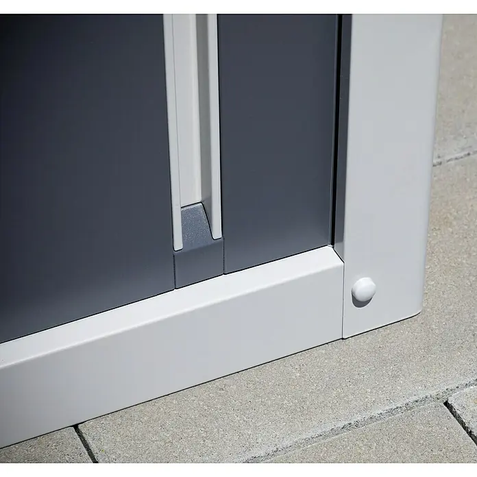 Trimetals Geräteschrank Guardian D63 - Außenbreite inkl. Dachüberstand: 176 cm, Außentiefe inkl. Dachüberstand: 89 cm, Stahl, Lichtgrau - Detailansicht eines grauen Metallschranks mit weißen Rahmen und Griff. Der Schrank steht auf einem gepflasterten Untergrund.