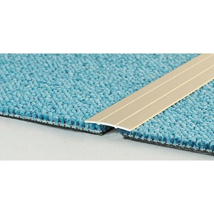 LOGOCLIC Übergangsprofil 132 - Sahara, 1 m x 38 mm x 2,5 mm, Montageart: Kleben - Nahaufnahme eines goldfarbenen Übergangsprofils, das zwei Abschnitte von blauem Teppich auf einem hellen Untergrund verbindet.