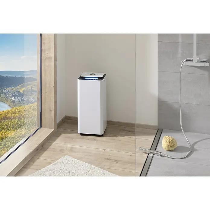 Proklima Luftentfeuchter - 400 W, Entfeuchtungsleistung: 20 l/Tag, L x B x H: 26,2 x 26,2 x 59 cm, Rollen - Das Bild zeigt einen weißen Luftreiniger in einem modernen Badezimmer. Er steht neben einer Glasduschkabine.
