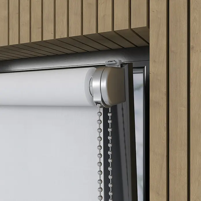 Verdunkelungsrollo Luxus - B x H: 160 x 190 cm, Weiß - Nahaufnahme einer weißen Rollgardine mit silbernem Kettenzug vor einer Holzwand, die für Privatsphäre und Lichtschutz sorgt.