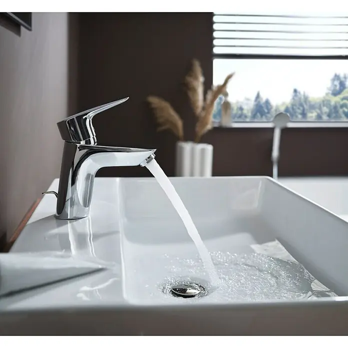 Hansgrohe Juego de lavabo Xanuia - 48 x 60 cm, Orificios para grifo: Medio, Con desbordamiento - Grifo cromado brillante sobre un moderno lavabo blanco con agua corriente, destacando su diseño elegante y su funcionalidad.