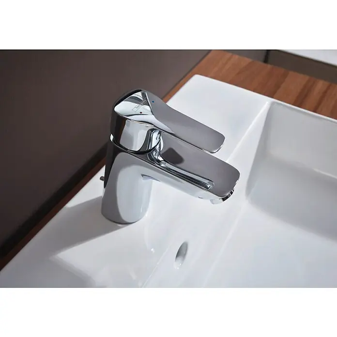 Hansgrohe Juego de lavabo Xanuia - 48 x 60 cm, Orificios para grifo: Medio, Con desbordamiento - Primer plano de un moderno grifo de baño cromado sobre un lavabo blanco. El diseño es elegante y contemporáneo, perfecto para cualquier baño.