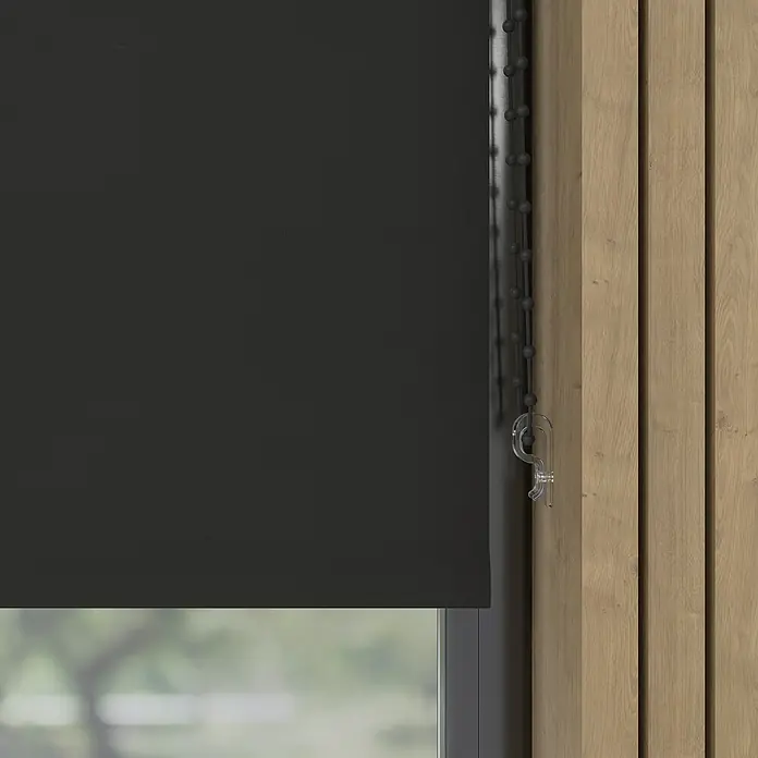 Verdunkelungsrollo - B x H: 170 x 190 cm, Dark, 100 % Polyester - Eine Nahaufnahme eines schwarzen Rollos vor einem Fenster mit einer Holzwand. Das Rollo ist teilweise heruntergelassen.