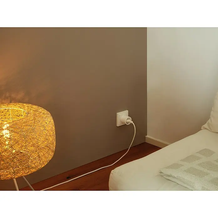 Osram Smart+ Smart-Steckdose matter - Innen, Weiß, 2 Stk. - Ein leuchtender kugelförmiger Lampenschirm aus hellem Garn, mit einem weißen Stromkabel, das in eine Steckdose an der Wand führt.