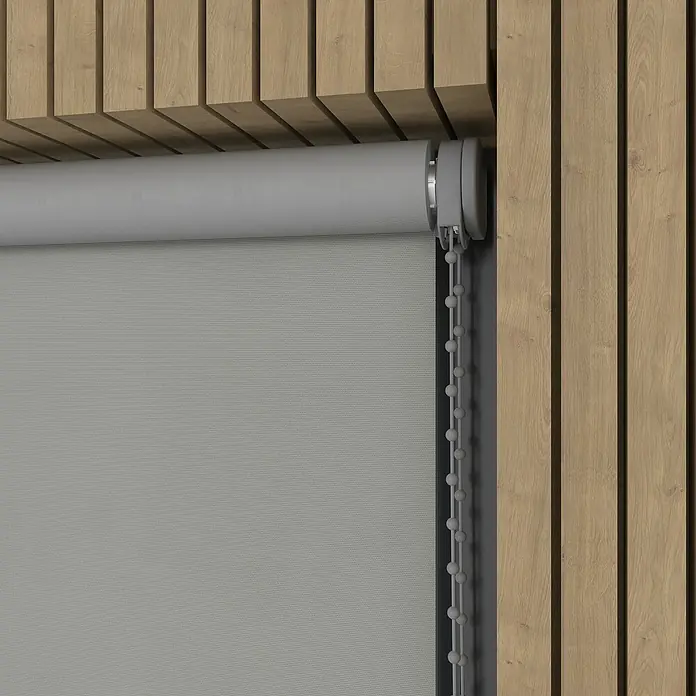 Verdunkelungsrollo - B x H: 200 x 190 cm, Kalkstein, 100 % Polyester - Nahaufnahme einer grauen Rollo mit Kettenzug vor einer hölzernen Wandverkleidung, die ein modernes und minimalistisches Design zeigt.