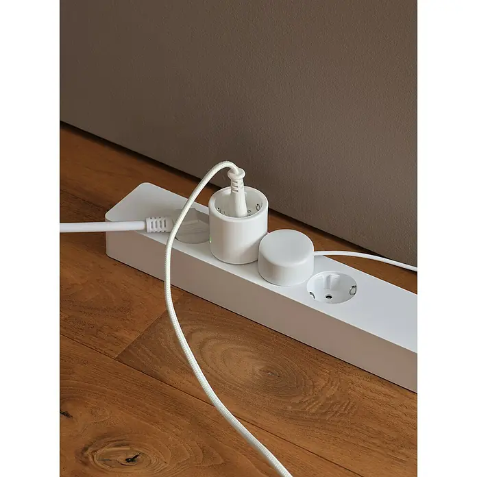 Osram Smart+ Smart-Steckdose matter - Innen, Weiß, 2 Stk. - Weiße Steckdosenleiste mit Stecker auf Holzboden, minimalistisches Design für moderne Stromversorgungslösungen im Haus.