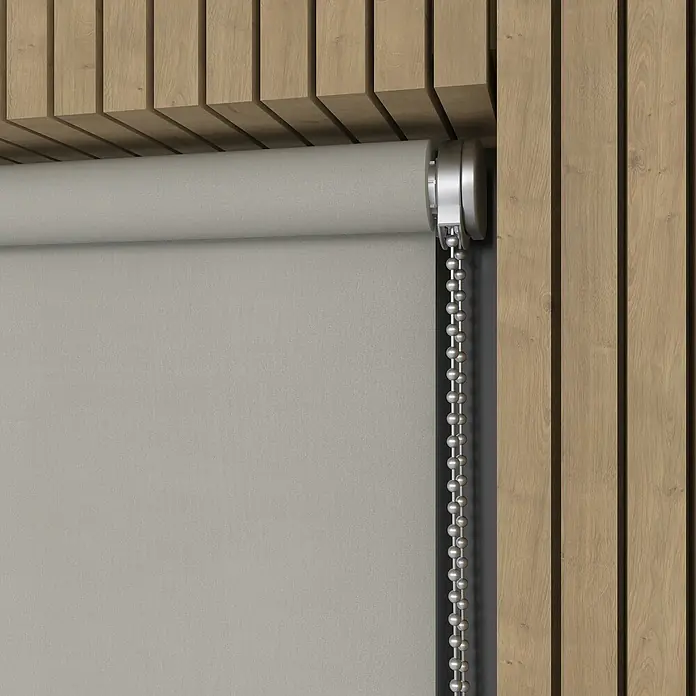 Verdunkelungsrollo Luxus - B x H: 230 x 190 cm, Hellgrau - Nahaufnahme einer grauen Rollo mit silberner Kette vor einem Hintergrund aus Holzpaneelen, die eine moderne Fensterdekoration zeigt.