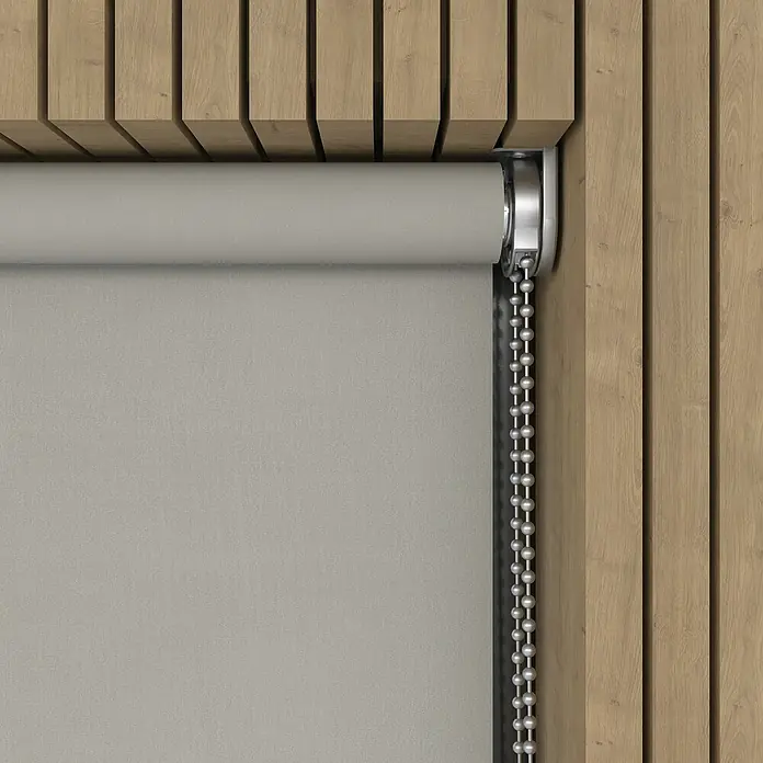 Verdunkelungsrollo Luxus - B x H: 230 x 190 cm, Hellgrau - Nahaufnahme einer grauen Rollmarkise mit silberner Kette vor einer Holzwand, die ein modernes und stilvolles Ambiente schafft.