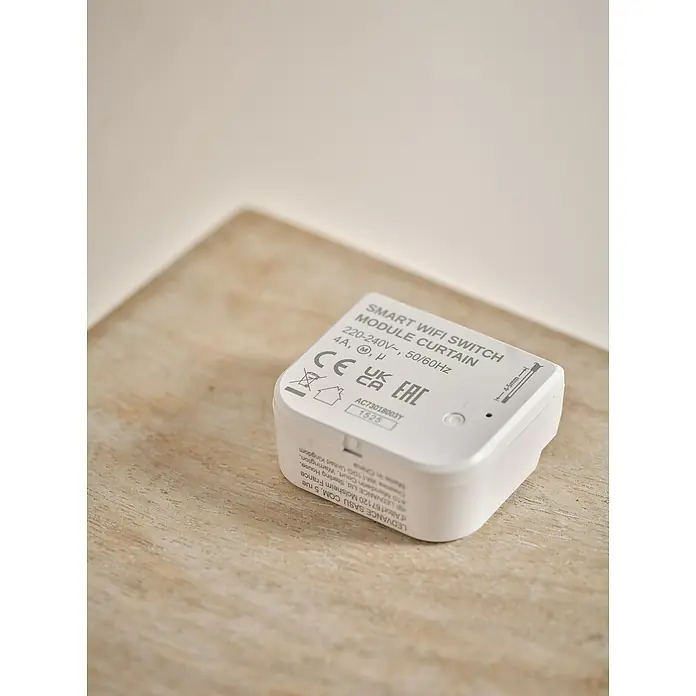 Osram Smart+ Schalter Vorhang - Weiß, Innen - Nahaufnahme eines LEDVANCE Smart WiFi Schaltermoduls für Vorhänge auf einem Holztisch, das Konnektivität und Kontrolle bietet.