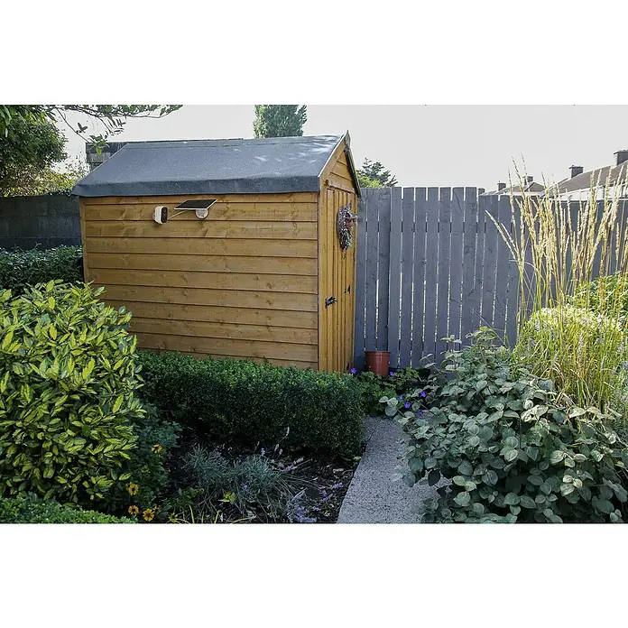 Osram Smart+ Überwachungskamera Battery Solar - Weiß - Ein Holzschuppen mit einer Überwachungskamera und Solarpanel, umgeben von üppigem Grün, bietet Sicherheit und Nachhaltigkeit im Garten.