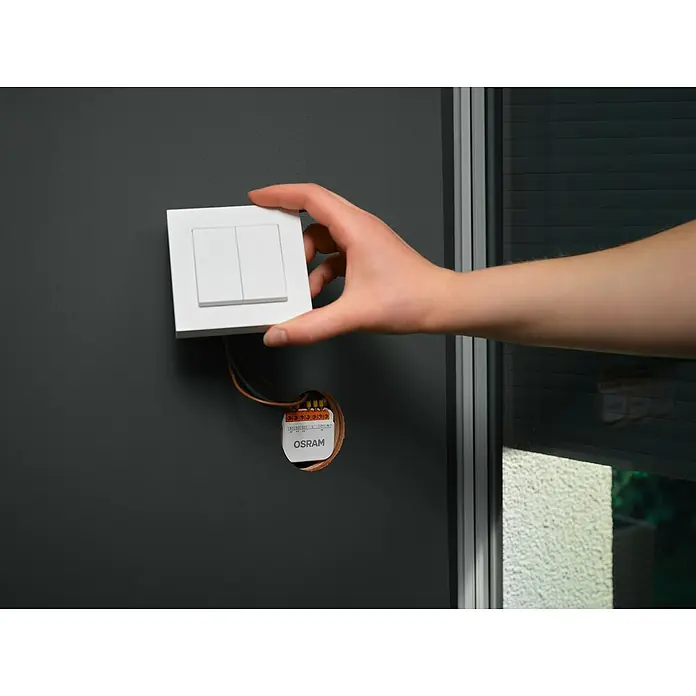 Osram Smart+ Schalter Vorhang - Weiß, Innen - Osram Lichtschalter wird an einer grauen Wand montiert, neben einem Fenster. Ideal für moderne Wohnräume und einfache Installation.