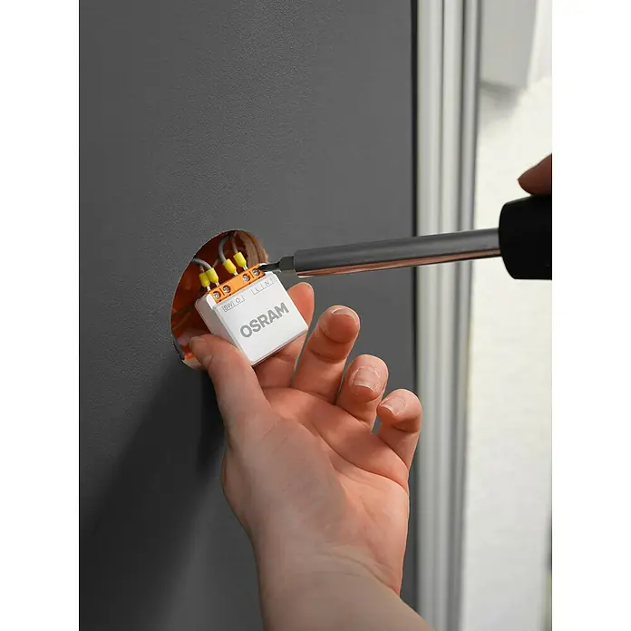 Osram Smart+ Schalter 1CH - Weiß, Innen - Installation eines OSRAM Smart Home Geräts mit einem Schraubendreher in einer Wand für intelligentes Lichtmanagement.