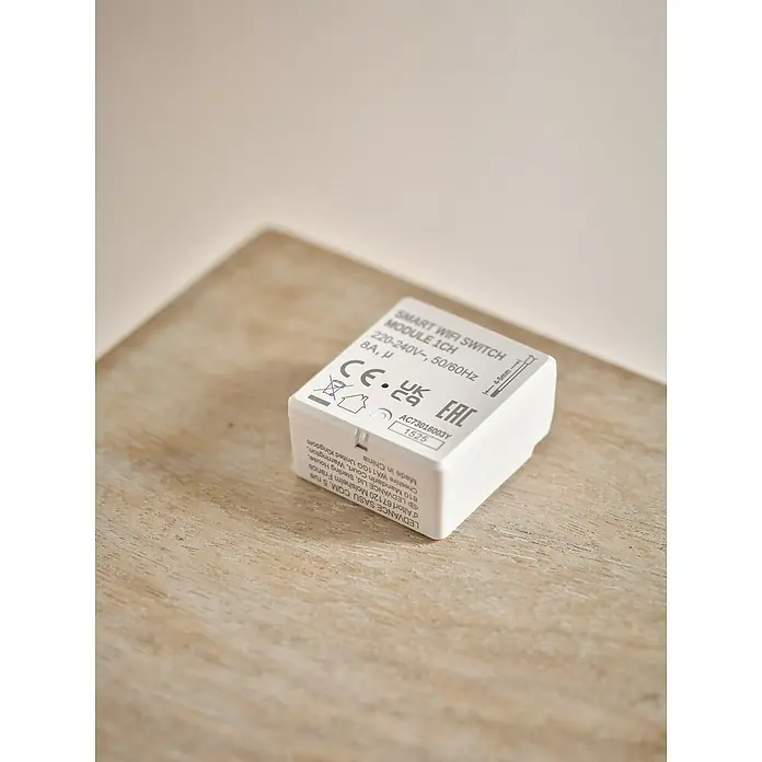 Osram Smart+ Schalter 1CH - Weiß, Innen - Nahaufnahme eines Smart WIFI Switch Moduls 1CH, das auf einer Holzoberfläche platziert ist.