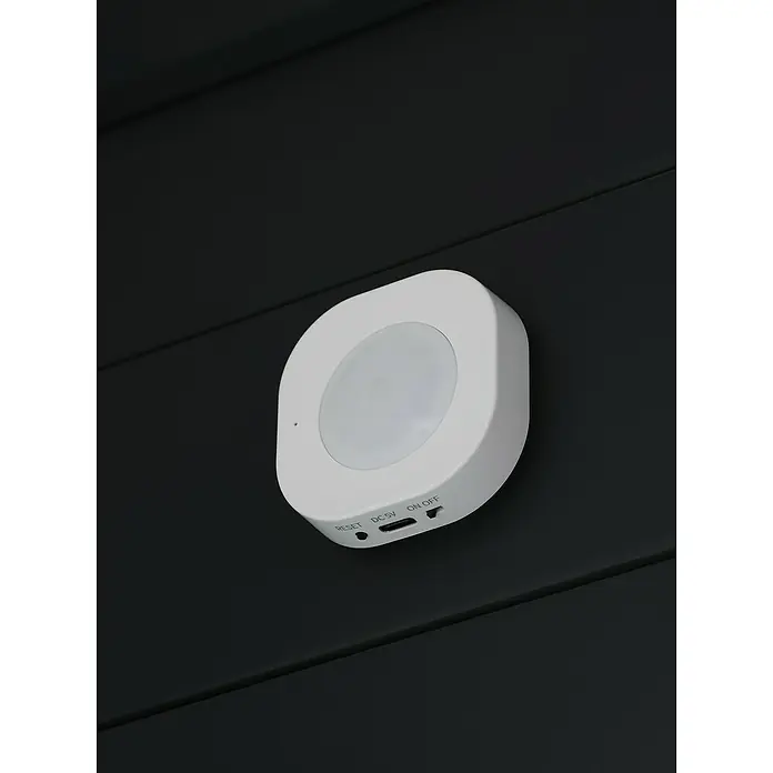 Osram Smart+ Bewegungsmelder - Weiß - Nahaufnahme eines weißen, runden Bewegungsmelders an einer dunklen Wand.