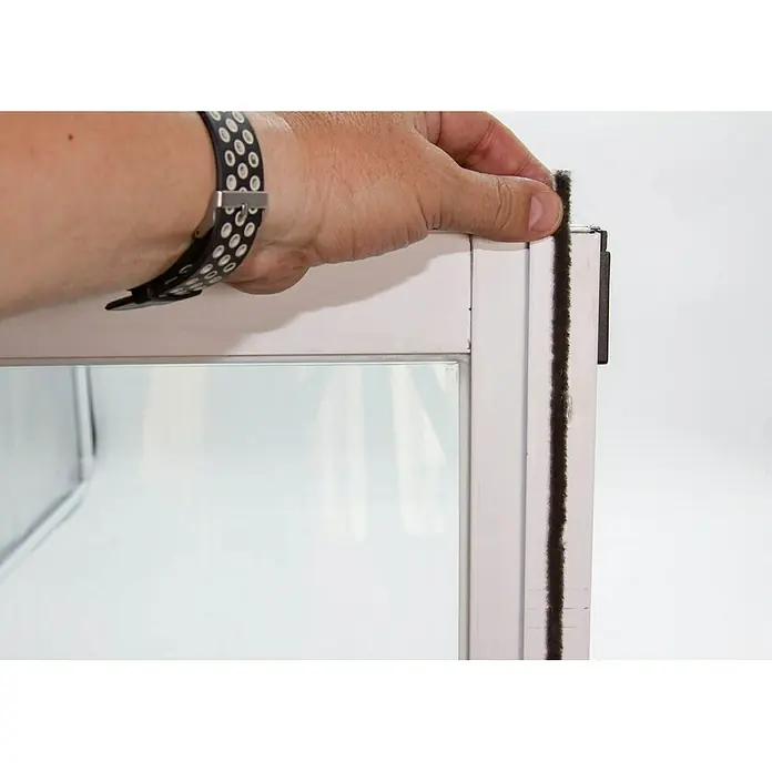 Burlete para ventanas Flecos - Blanco, Largo: 6 m, Ventana - Imagen de un marco de ventana con burletes aplicadas por una mano. El producto protege contra corrientes de aire y ahorra energía.
