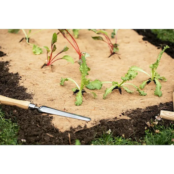 Windhager Jutevliesmatte - L x B: 4 x 0,75 m, Jutenaturfaser - Nahaufnahme von Pflanzbeet mit Beetabdeckung und kleinem Gartengerät. Die Beetabdeckung schützt junge Pflanzen und den Boden.